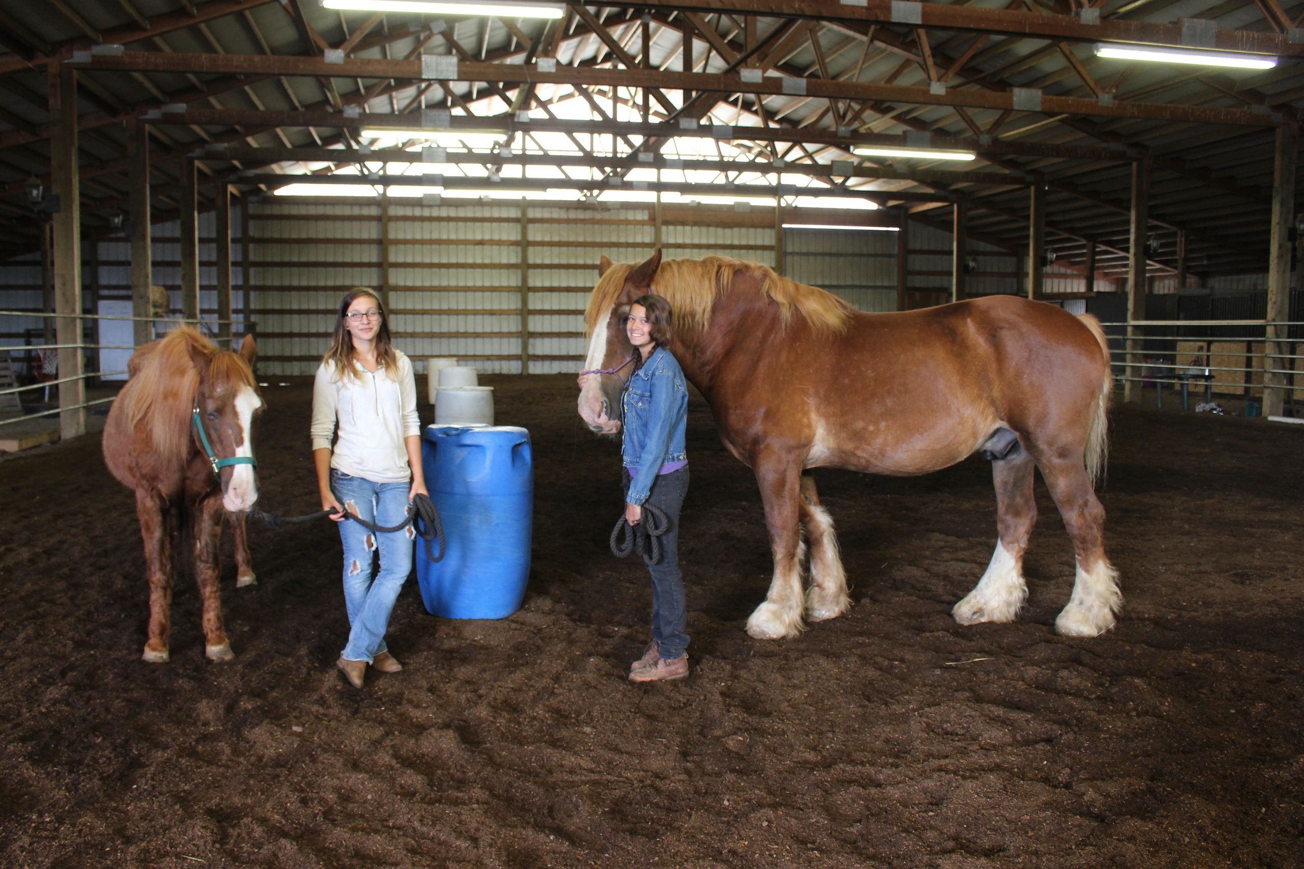 Two young women with horses in the arena at Harmony Ranch