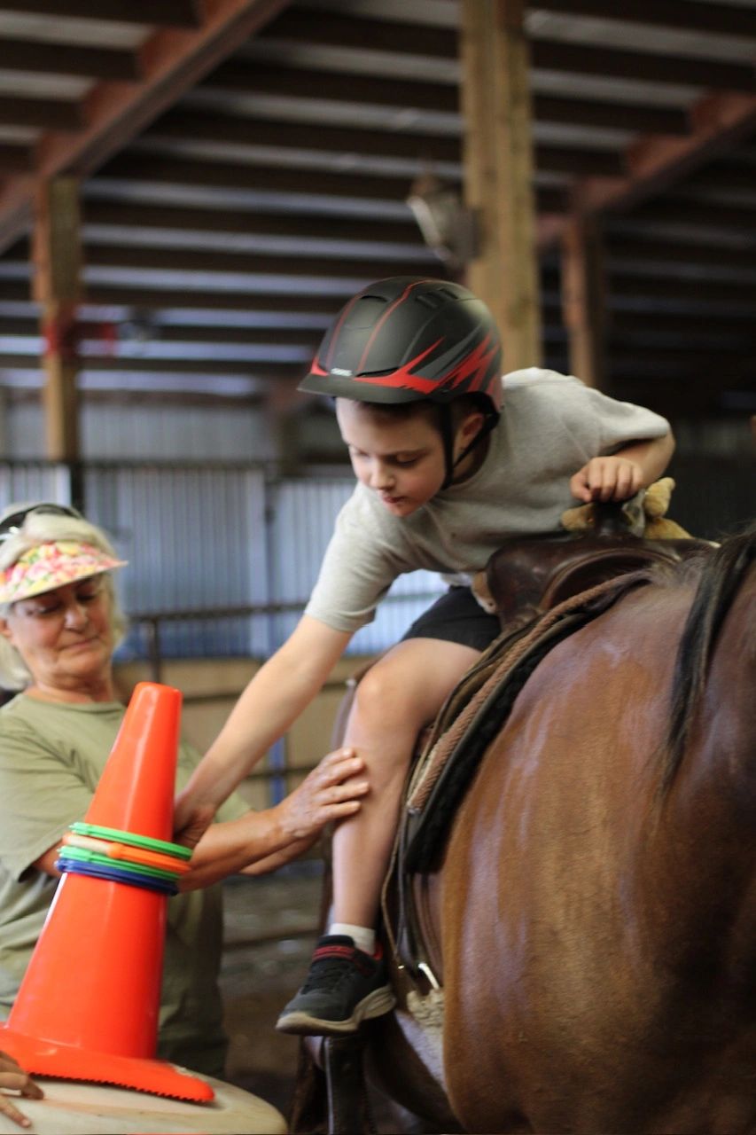 Child on horseback during riding lesson with instructor